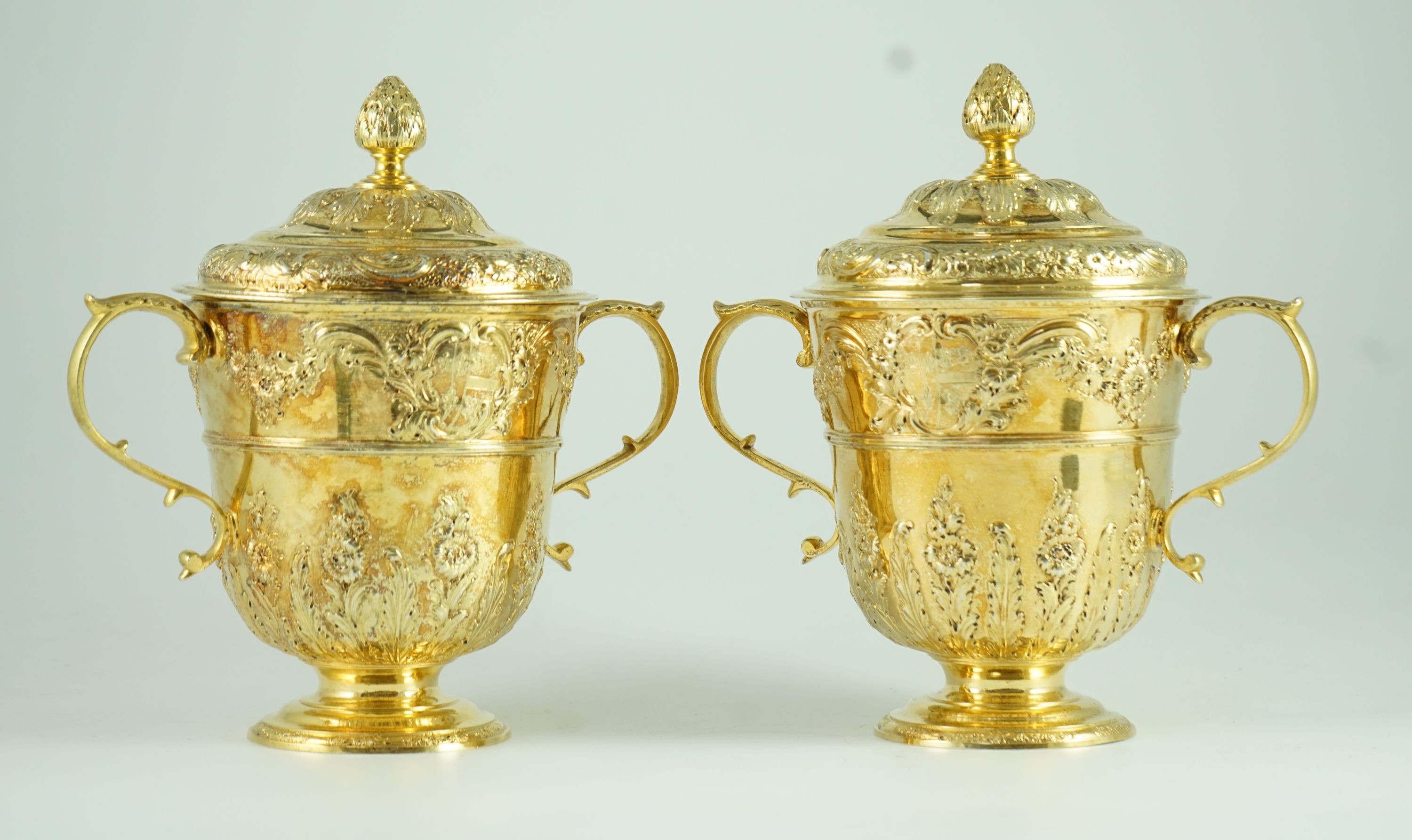 A good pair of George II embossed silver gilt two handled pedestal cups and covers, by Benjamin Gignac